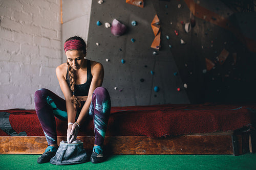 Woman wall climber coating hands with gripping powder