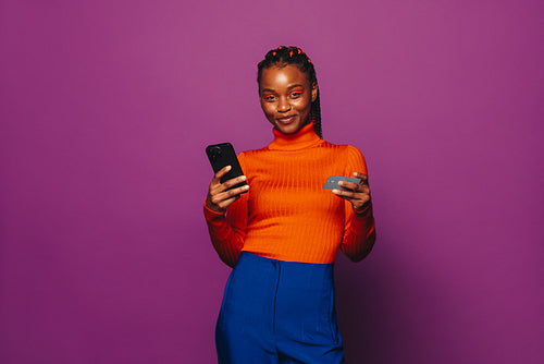 Happy gen z woman using online shopping app on smartphone for cashless payment with credit card