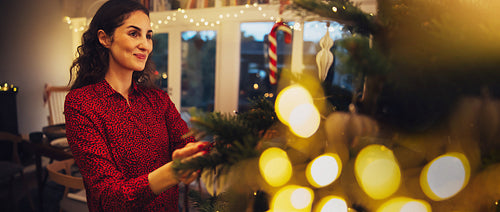 Christmas holiday moments - woman decorating christmas tree inside her cozy family house full of warm lights