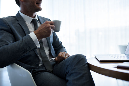 Businessman having coffee in office lobby