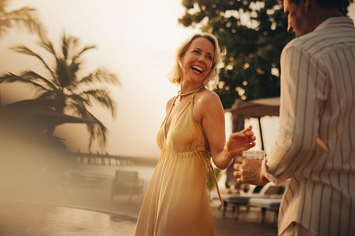 Elegant couple enjoying sunset drinks and dancing at resort