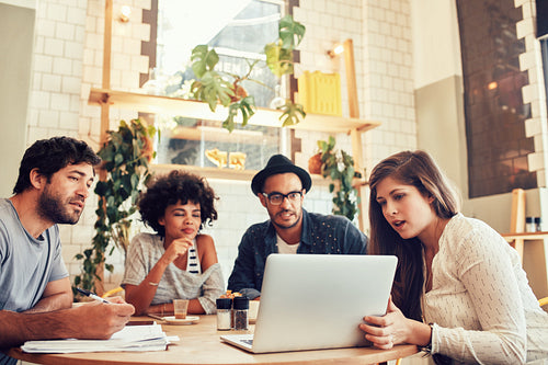 Creative team sitting at cafe and looking at a laptop