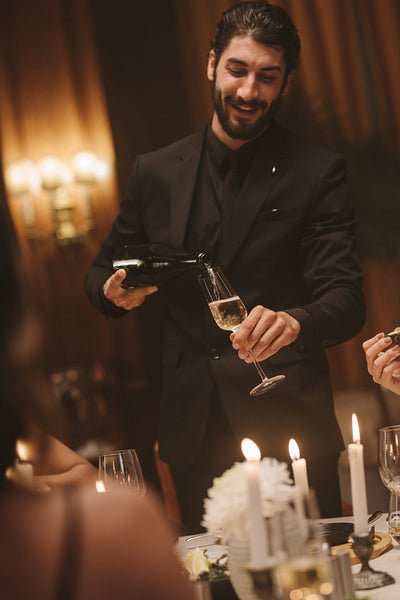 Man serving drinks to friends at dinner party