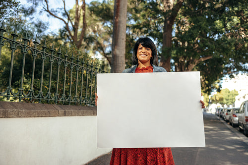 Female activist holding a white banner outdoors during the day