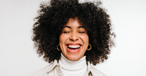 Woman with curly hair laughing happily in a studio