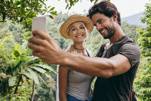 Smiling young couple taking selfie with waterfall