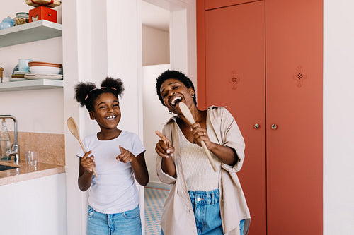 Woman and her daughter singing and dancing with joy at home