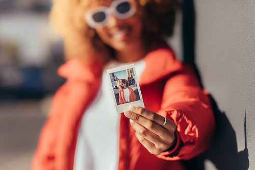 Portrait of a tourist woman holding a polaroid photo