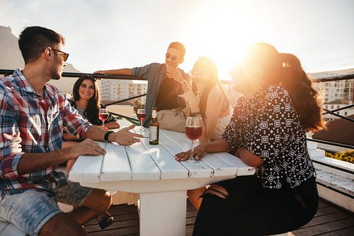 Young people having rooftop party in evening.