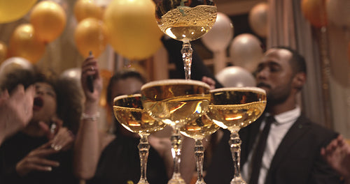 Pyramid of champagne glasses with people dancing