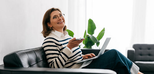 Remote browsing shows the woman working from home on a couch with a laptop in the living room