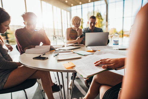 Young students sitting around a table in library