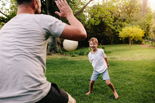 Happy young family playing with ball in backyard