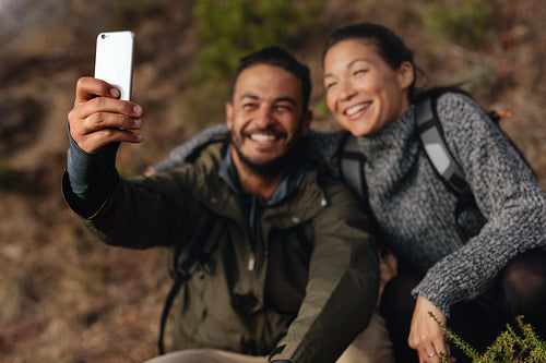 Young couple hiking taking selfie with smart phone