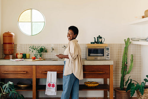 Happy Brazilian woman smiling while preparing to cook in the kitchen, with ingredients on counter