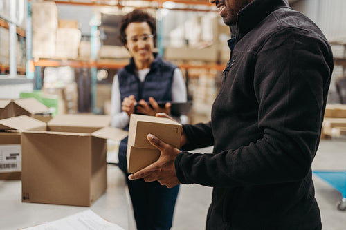 Happy warehouse worker packing orders in a logistics centre