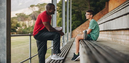Sports coach talking to his student outside in a school