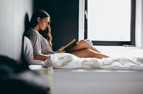 Young female on bed reading a book