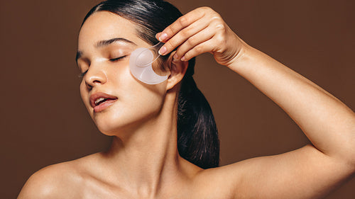 Anti-aging treatment; woman applying a gel patch under her eye