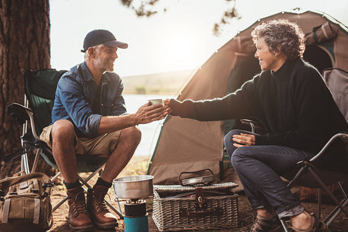 Mature couple with coffee camping by a lake 
