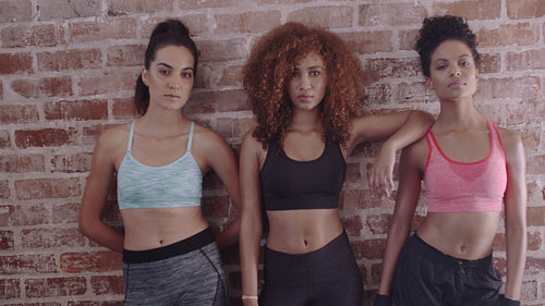 Fitness women standing against brick wall in gym