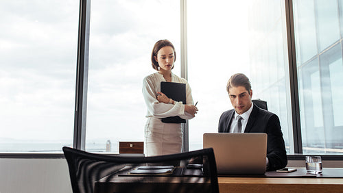 Businessman working on laptop with secretary