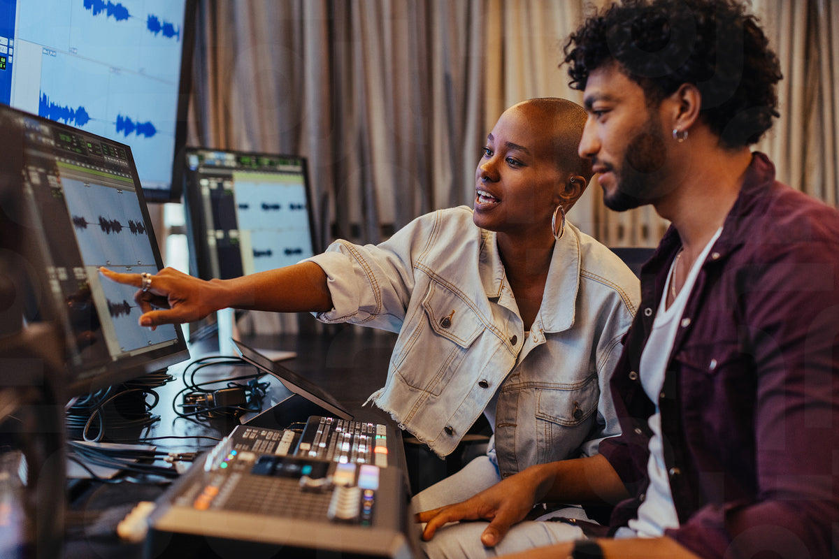 Creative professionals collaborating in a music studio with modern equ ...