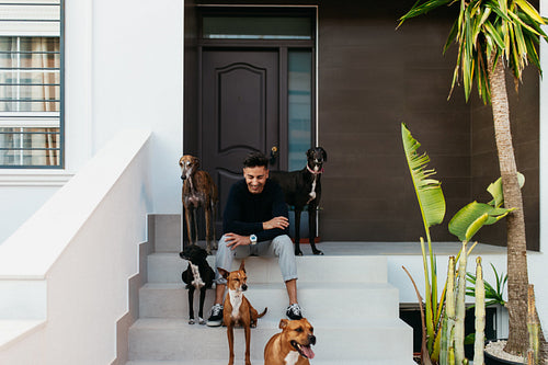 Happy pet owner sitting on the porch with his dogs
