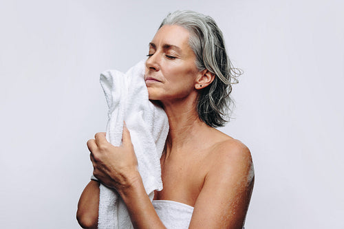 Woman drying face with towel in studio