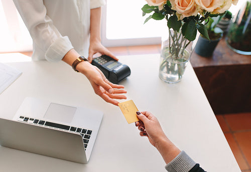 Female florist taking credit card from buyer hand