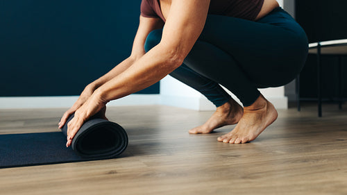 Senior woman rolling up her yoga mat after practice
