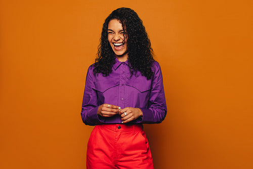 Stylish woman laughing on colourful background