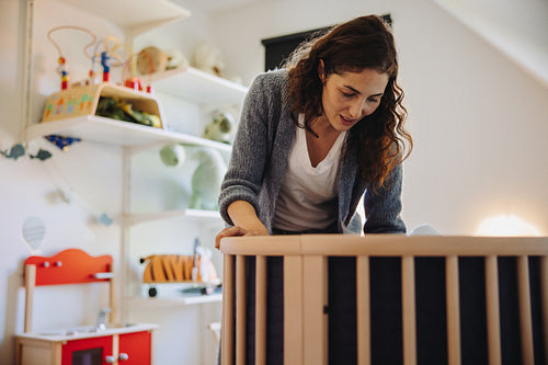 Mother putting her baby to sleep in crib