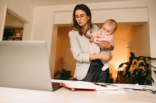 Professional interior designer holding her baby in her home offi