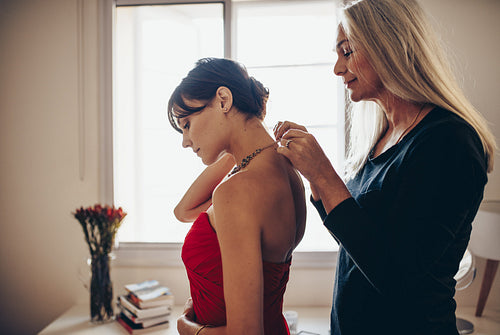 Old mother helping her daughter put on a necklace