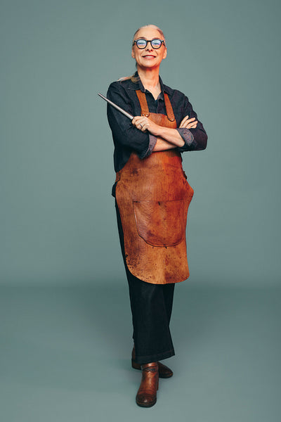 Female goldsmith holding a ring mandrel in a studio