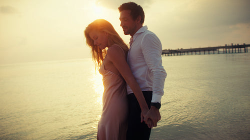 Romantic couple enjoys a beautiful tropical sunset on a luxurious beach vacation