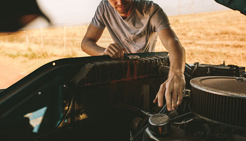 Man repairing his car on highway