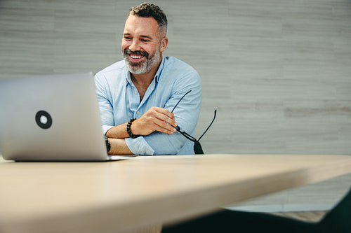 Happy businessman attending an online meeting in an office