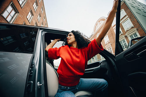 Woman getting out of car on city street during daily commute