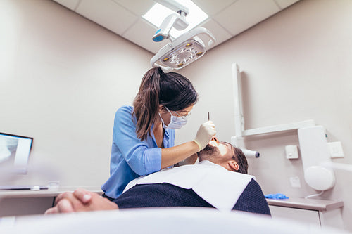 Female dentist examining a patient with tools