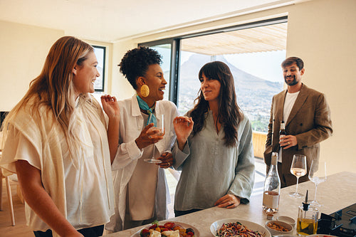 Close friends enjoying drinks and conversation in a modern home with a view