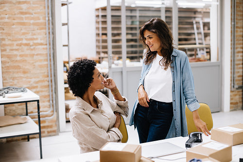 Two online store owners having a discussion in a warehouse
