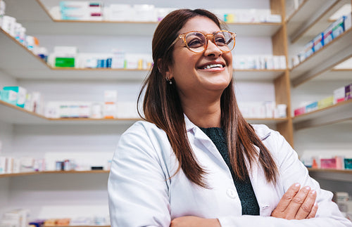 Happy female pharmacist standing in a drug store