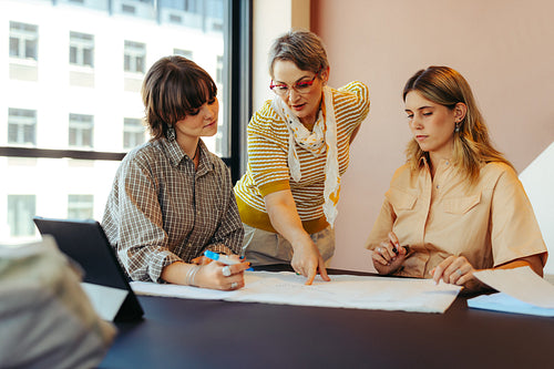 Professor guiding college students during a task in a modern classroom setting for effective learning and understanding