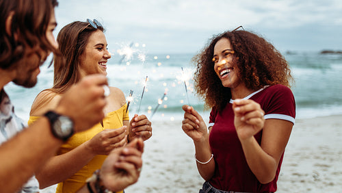 Diverse group of friends with sparklers at beach
