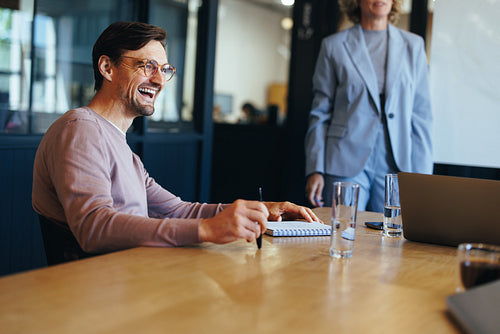 Happy business professional sitting in a meeting with his team