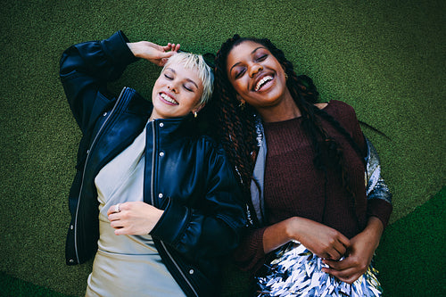 Women laugh together while relaxing on grass outdoors