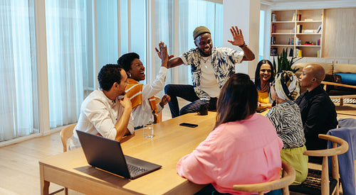 Diverse team in an office celebrating success with a high-five