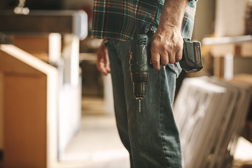 Carpenter with drilling machine in hand at workshop
